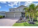 Charming two-story home showcasing a brick driveway, two-car garage, lush landscaping, and a welcoming front entrance at 11605 Cleyera Ct, Riverview, FL 33579