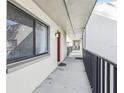 Exterior walkway view with black metal railings leads to a red condo door, offering seamless access to the unit at 11706 Raintree Village Blvd # D, Temple Terrace, FL 33617