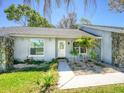 Inviting home entrance with a white front door and decorative landscaping at 2988 Pinewood Run, Palm Harbor, FL 34684