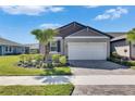 Single-story home featuring a well-manicured lawn and a two-car garage, enhanced by meticulous landscaping at 3753 Maxwell Park Dr, Sun City Center, FL 33573