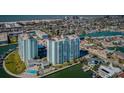 Aerial view of the condo building featuring a pool, lush landscaping, and waterfront access at 420 64Th Ave # 907, St Pete Beach, FL 33706