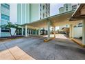 View of the condo building entrance featuring a covered driveway and manicured landscaping at 420 64Th Ave # 907, St Pete Beach, FL 33706