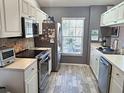 Fully equipped kitchen with stainless steel appliances, white cabinets, and tiled backsplash at 4275 Castlebridge Ln # 1325, Sarasota, FL 34238