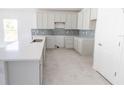 Bright kitchen features gray cabinets, tile backsplash, stainless steel sink, and tile floors at 434 Albatross Rd, Rotonda West, FL 33947