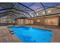 A generously sized screened pool with brick paver deck and seamless access to the home's interior at twilight at 902 Marco Ne Dr, St Petersburg, FL 33702