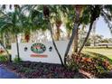 Entrance sign for Harbor Greens, a private residential community, framed by mature palm trees and colorful plants at 9433 Harbor Greens Way # 405, Seminole, FL 33776