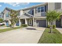 Charming gray townhome featuring a one-car garage, a well-manicured lawn, and beautiful, decorative trees at 10912 Quickwater Ct, Riverview, FL 33569