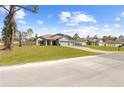 Exterior view showcasing the property and neighborhood; light gray with nice lawn and three-car garage at 11092 Jenny Wren Rd, Weeki Wachee, FL 34614