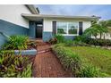 Inviting front entrance featuring a brick pathway and lush tropical landscaping at 13548 Bellewood Ave, Seminole, FL 33776