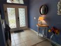 Welcoming blue foyer features decorative glass doors, a round mirror, and a nautical-themed side table at 2069 Overbrook Ln, Spring Hill, FL 34606