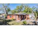 View of the rear exterior of the red brick home with a small patio and lush green lawn at 2410 E Palifox St, Tampa, FL 33610