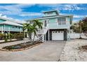 Beautiful two-story coastal home with single garage, stairs to the balcony, stone accents, and palm trees at 311 Poinsettia Rd, Anna Maria, FL 34216