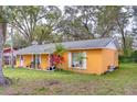 Quaint yellow home featuring lush green lawn and mature shade trees at 40111 Pretty Redbird Rd, Zephyrhills, FL 33540