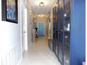 Bright hallway with display cabinets, tiled floors, and a view of the front door at 6494 Beverly Hills Dr, Zephyrhills, FL 33541