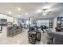 Open-concept living room with white cabinets, granite counters, stainless appliances, dining area, and comfortable gray couches at 6494 Beverly Hills Dr, Zephyrhills, FL 33541