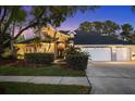 Beautiful home exterior at dusk, featuring lush landscaping and a three car garage at 12117 Clear Harbor Dr, Tampa, FL 33626