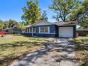 A blue exterior home with a one-car garage and a front lawn with cracked driveway at 1610 Hughes Dr, Plant City, FL 33563