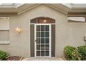 A charming front entryway features a white-framed screen door and decorative exterior lighting at 2129 Acadia Greens Dr, Sun City Center, FL 33573