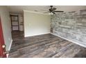 Inviting living room with decorative wood paneling, updated flooring, and a ceiling fan at 25590 Olympia Rd, Brooksville, FL 34601