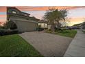 Paver driveway leading to a two car garage with manicured lawn at 30280 Southernwood Ct, Wesley Chapel, FL 33543