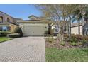 Charming home with a brick driveway, a two-car garage, and manicured landscaping at 30280 Southernwood Ct, Wesley Chapel, FL 33543
