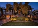 Beautiful two-story home with well-manicured landscaping, including palm trees and illuminated shrubbery, and a two-car garage at 315 Manatee Ln, Tarpon Springs, FL 34689