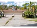Charming home featuring a tile roof, two-car garage, and beautiful tropical landscaping with mature palm trees at 3798 Darston St, Palm Harbor, FL 34685