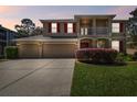 Charming two-story home features a spacious three-car garage, red shutters and a well-manicured lawn at 7309 Night Heron Dr, Land O Lakes, FL 34637