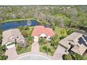 Aerial view of the property, highlighting the tile roof, pool, landscaping, and serene pond setting at 8057 Rio Bella Pl, Bradenton, FL 34201