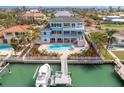 Aerial view of a backyard with a pool, spa, tropical landscaping, and a private boat dock at 440 Capri Blvd, Treasure Island, FL 33706