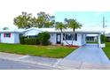 Inviting single-story home with a carport, white exterior, lush lawn, and mature palm trees in a tranquil setting at 4517 100Th N Ave, Pinellas Park, FL 33782