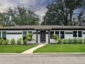 Charming single-story home featuring a well-manicured lawn, tidy shrubs, and symmetrical design elements at 525 Lamara Ne Way, St Petersburg, FL 33704