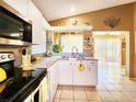 Well-lit kitchen with white cabinets, tile floors, and a view to the outside at 7534 Beacon Woods Dr, Hudson, FL 34667