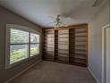 Bedroom view showing a built-in bookcase, ceiling fan, and large window for plenty of light at 8530 Alexandra Arbor Ln, Temple Terrace, FL 33637