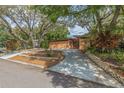 Inviting home exterior surrounded by mature trees, landscaping, and a long driveway providing ample parking at 1301 45Th N Ave, St Petersburg, FL 33703