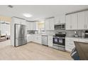 Bright kitchen features stainless steel appliances, gray backsplash, granite counters, and white cabinets at 1319 Leland Dr # 101, Sun City Center, FL 33573