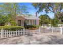 View of the exterior of the home, displaying a white picket fence and tropical landscaping at 1874 N Washington Ave, Clearwater, FL 33755