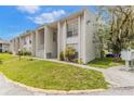White townhouse with a green lawn, short sidewalk, and trees, under a blue sky with white clouds at 2625 State Road 590 # 2612, Clearwater, FL 33759