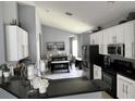Modern kitchen featuring white cabinets, stainless steel appliances, and black countertops at 5229 Clover Mist Dr, Apollo Beach, FL 33572