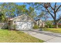 Beautiful home with a well-kept lawn, complemented by mature trees and a two-car garage at 7440 Mint Julep Dr, Riverview, FL 33578