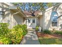 Inviting front entrance featuring double doors, complemented by lush landscaping and a charming chair at 7440 Mint Julep Dr, Riverview, FL 33578