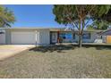 Lovely home with an attached garage and brick accents, surrounded by mature trees at 10915 Hammock Dr, Largo, FL 33774