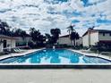 A beautiful community pool with lounge chairs and clear water on a partly cloudy day at 1620 58Th Ave. S. # 1, St Petersburg, FL 33712