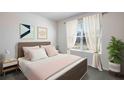 Cozy bedroom with soft pastel bedding, a window with sheer curtains, and decorative wall art at 1706 Tahitian Sunrise Dr, Plant City, FL 33565