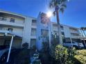 Exterior shot of building with covered parking, balcony access, and manicured landscaping at 215 Valencia Blvd # 205, Belleair Bluffs, FL 33770
