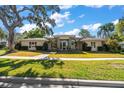 Charming home with a well-manicured lawn, mature trees, and a beautiful stone entryway at 217 Manatee Rd, Belleair, FL 33756