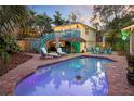 Inviting backyard oasis featuring a sparkling pool, tiki bar, upper deck and lounge area perfect for entertaining at 235 Aberdeen St, Dunedin, FL 34698