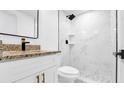 Sleek bathroom featuring a white vanity, granite countertop, and tiled shower with rain showerhead at 5712 Mallow St, New Port Richey, FL 34652