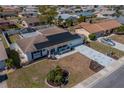 A neighborhood aerial view of a white single-story home with solar panels and unique, patterned driveway at 663 Allegheny Dr, Sun City Center, FL 33573