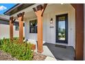 Inviting front porch showcasing sturdy wood pillars, a stylish black door, and lush landscaping at 8337 Abalone Loop, Parrish, FL 34219